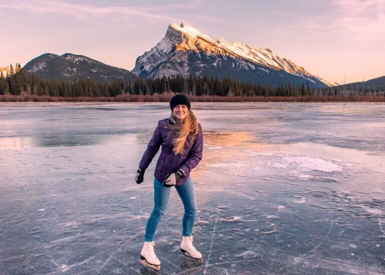 A lade ice skates on the frozen Vermilion Lakes in winter in Canmore
