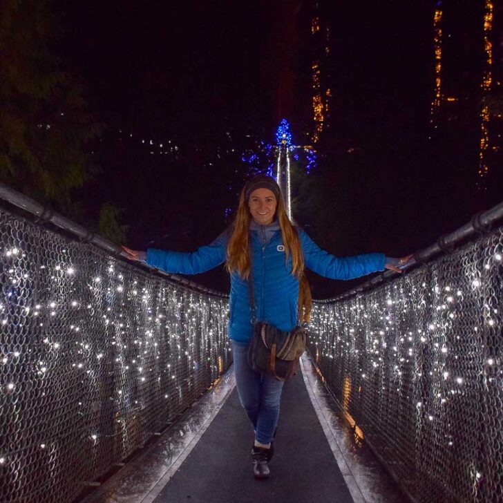 Bailey stands on the capilano suspension bridge at night surrounded by lights on a trip from Vancouver Canada