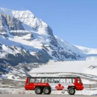 An Ice Explorer all-terrain vehicle parked with the Athabasca Glacier in the background on a summers day in Canada