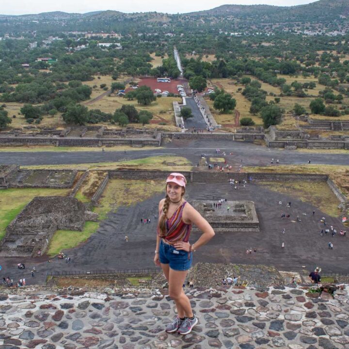 A lady stands at the top of The Pyramid of the Sun in Teotihuacan, Mexico
