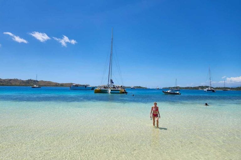 A woman walking up to the sand bar from the water with the Sabre catamaran behind her fiji
