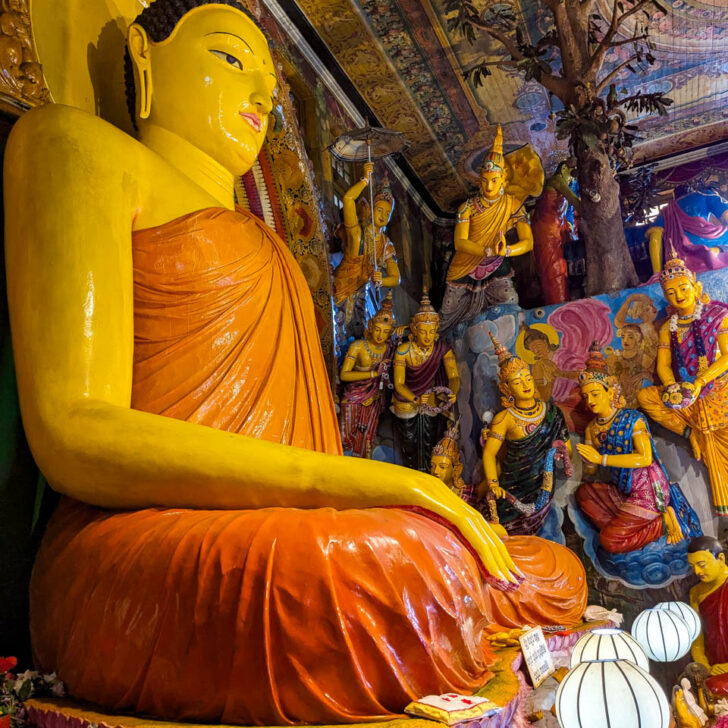 Looking at the large statue of the Buddha up close with other paintings in the background at the Gangarama temple Sri Lanka, Colombo