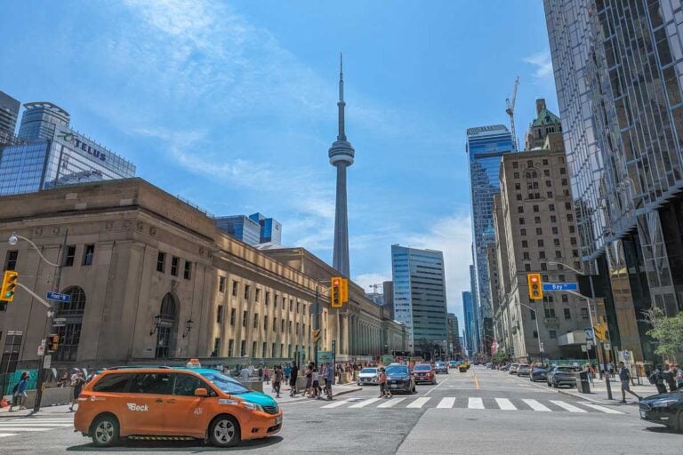 A taxi drives along a downtown Toronto road with the CN Tower in the background