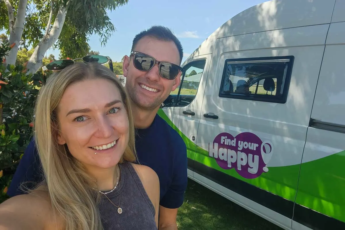 Daniel and Bailey smile with a JUCY campervan in the background in Australia
