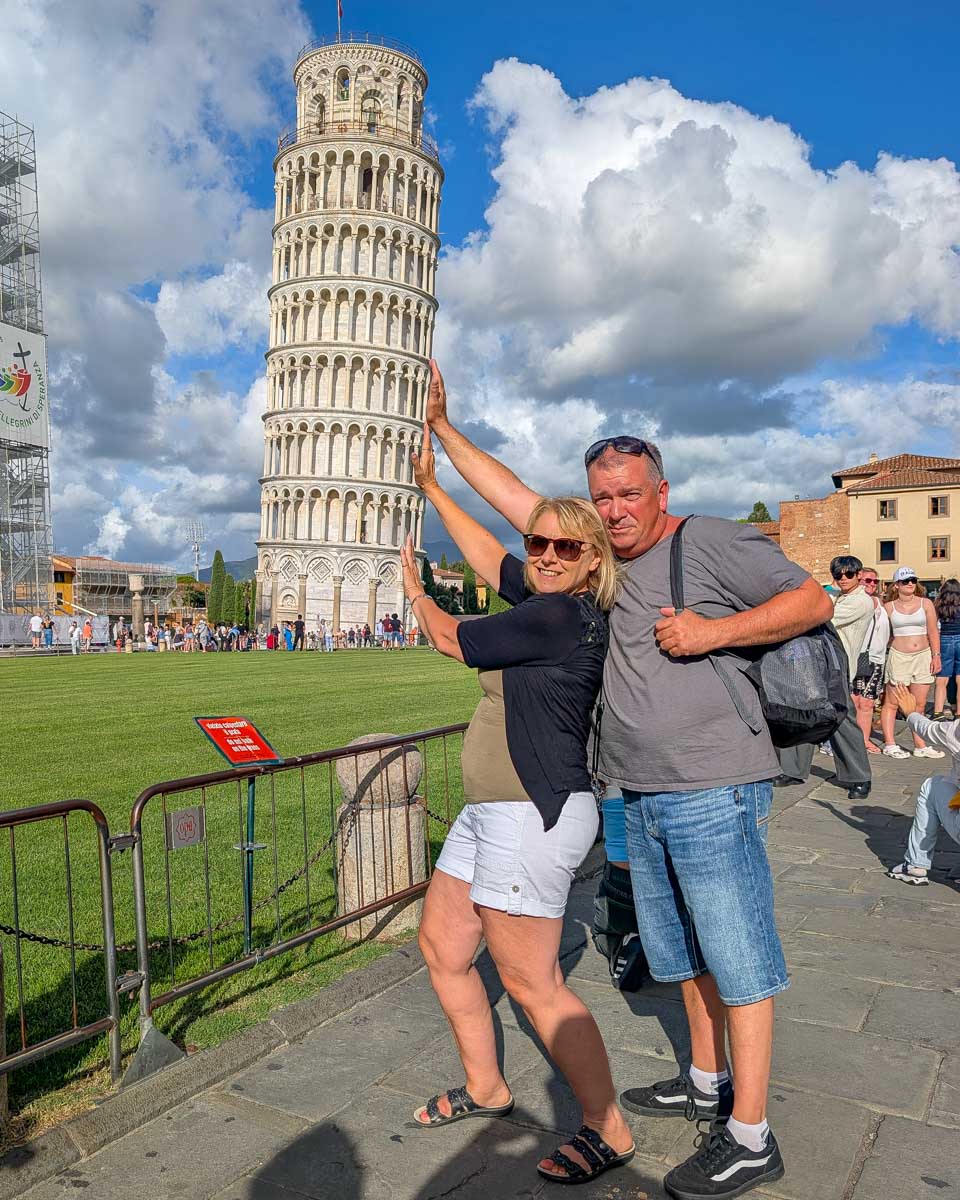Two-people-push-up-the-leaning-tower-of-Pisa-in-Pisa-Italy-on a tour from Florence
