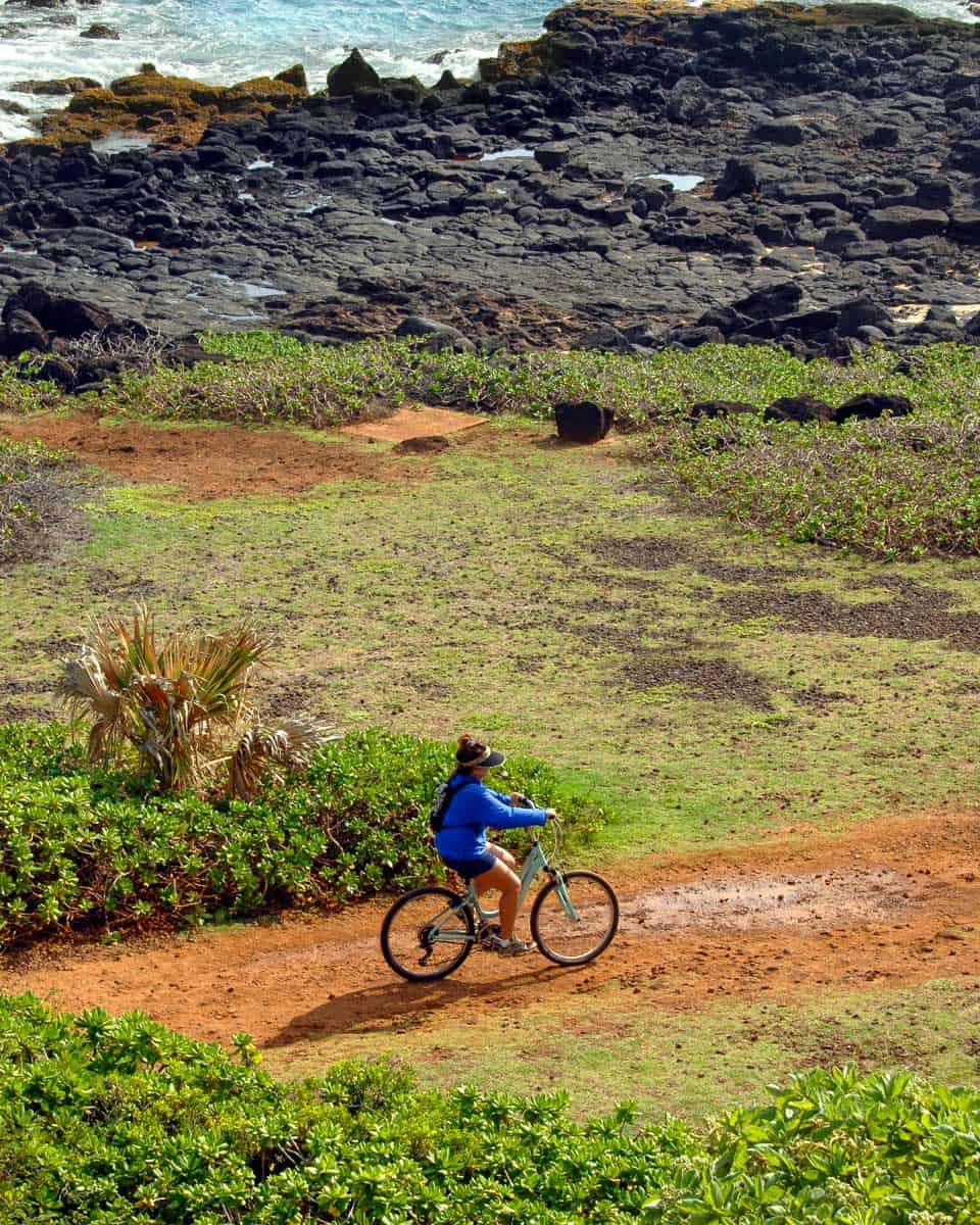 Biker takes the rugged trail along lava lined beaches on Kauai Hawaii