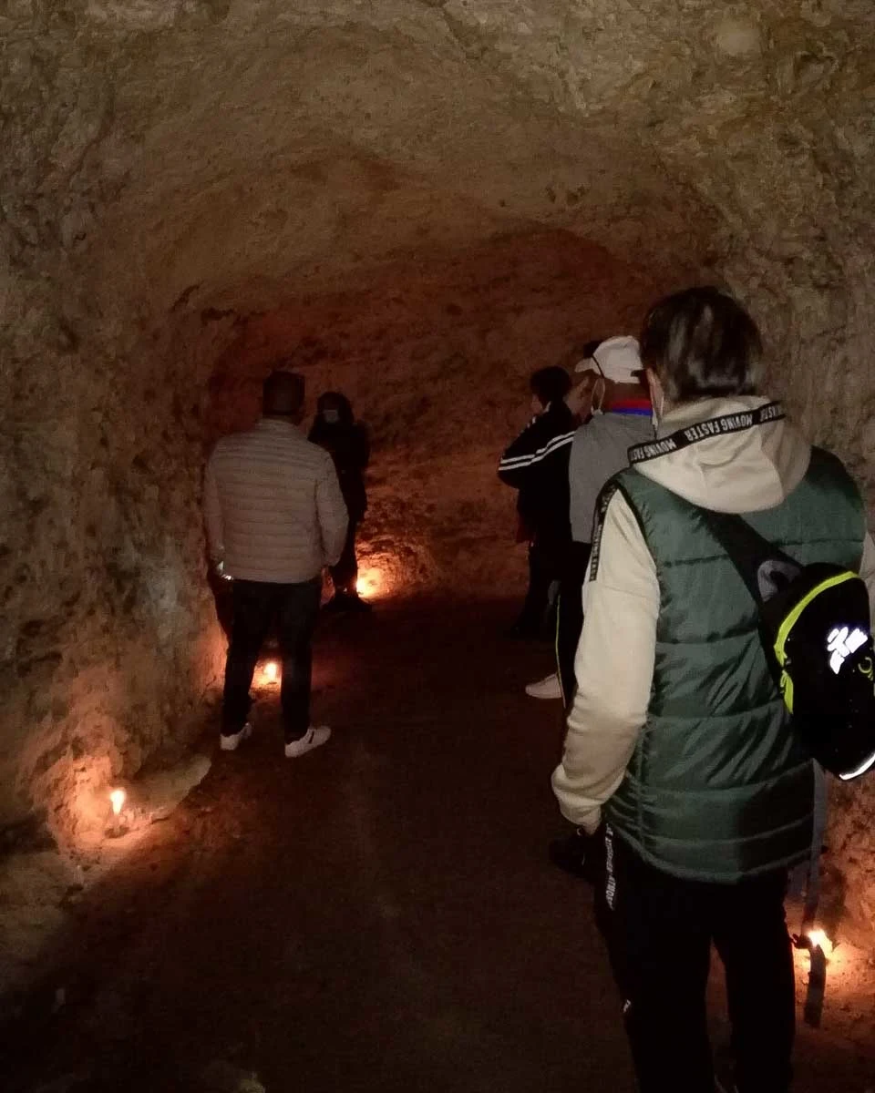 People in a candle lit underground tunnel on a tour in Cagliari Italy