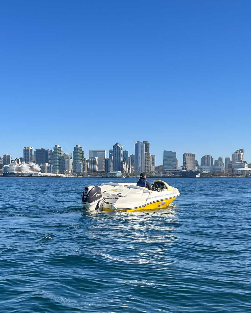 A speed boat out on the water with the San Diego skyline in the background