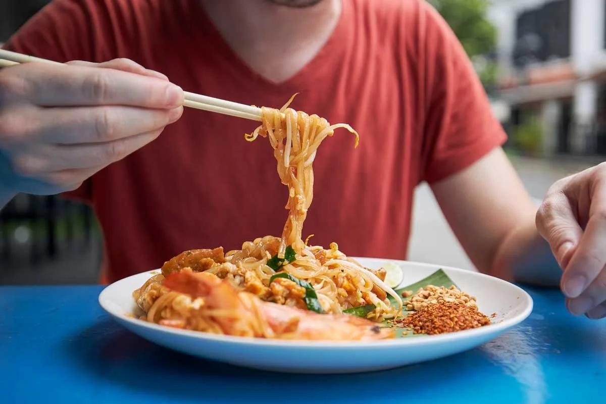A man eats pad thai in Bangkok Thailand