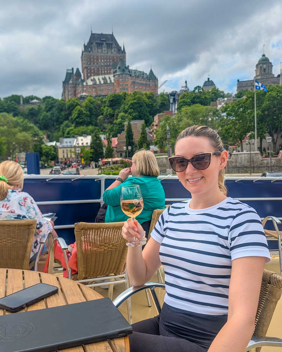 Bailey friend with drink and a view of Château Frontenac on a cruise in Quebec City, Canada