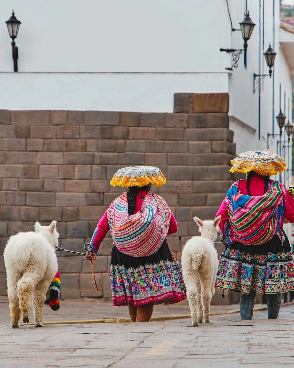 Two local women walk with llamas in Lucrepata Cusco Peru