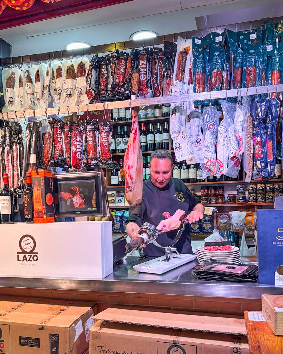 A man cuts meat at a market in Spain