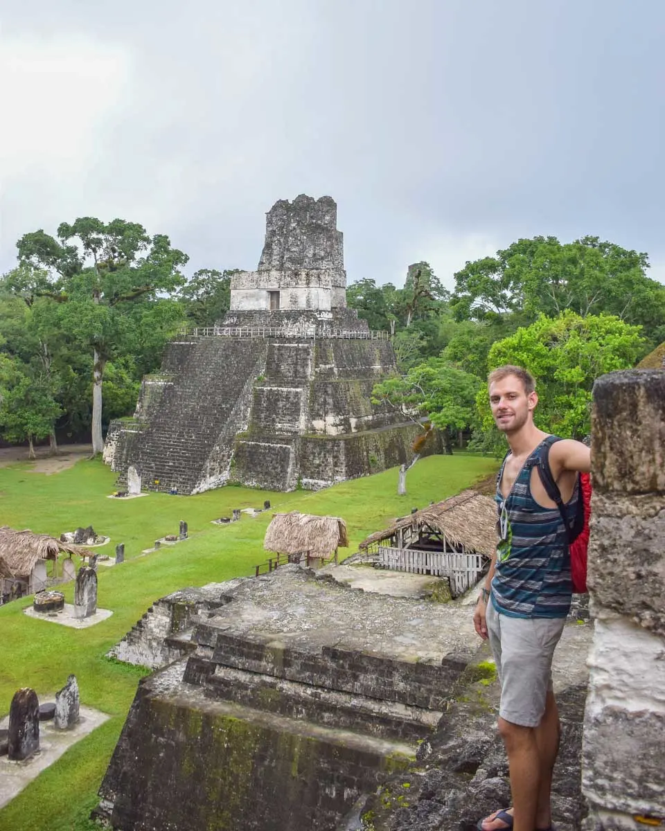 Daniel-stands-on-a-temple-in-Tikal-and-looks-down-at-the-restored-ruins on a tour from Belize