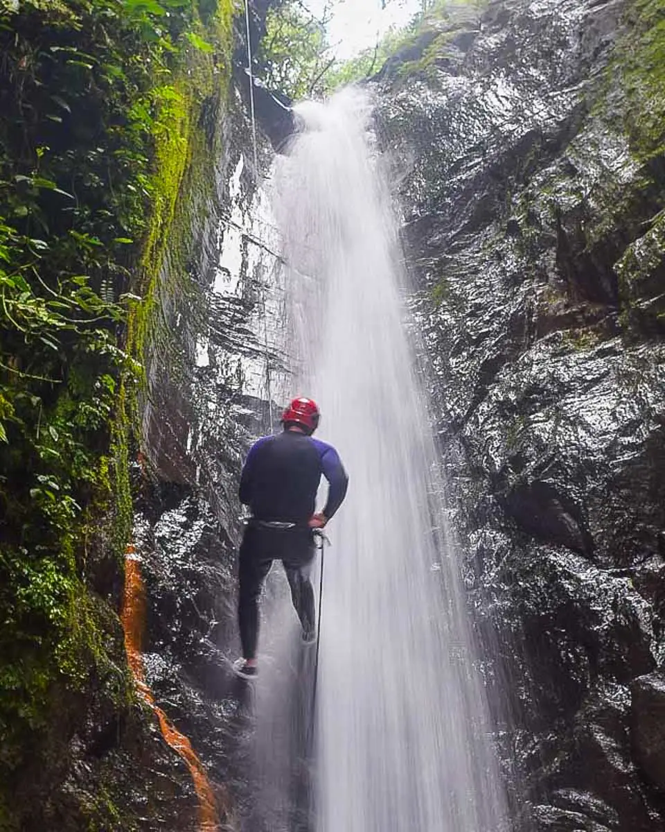 A person rappels down a waterfall canyoning in Dominica