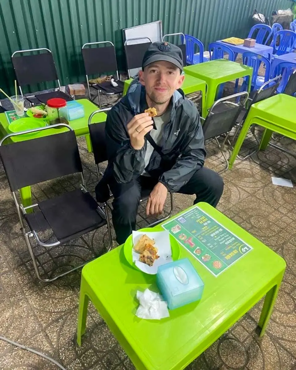 Jesse eating street food in Pham Ngu Lao Ward, Vietnam