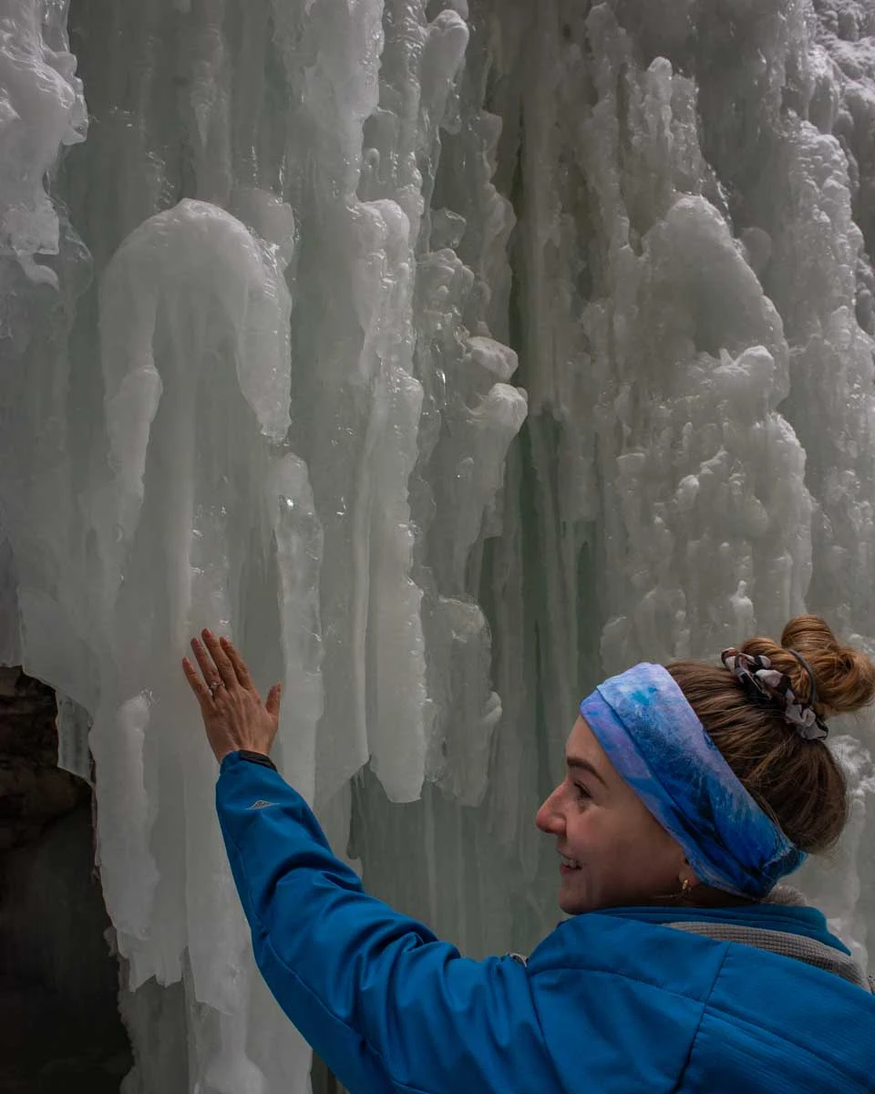Bailey-touches-one-of-the-ice-waterfalls-in-Korouoma Canyon on a tour from Rovaniemi, Finland