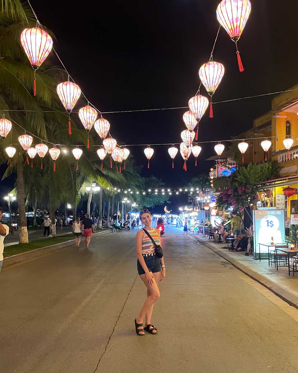 Brittni walks along a street in Hoi An at night