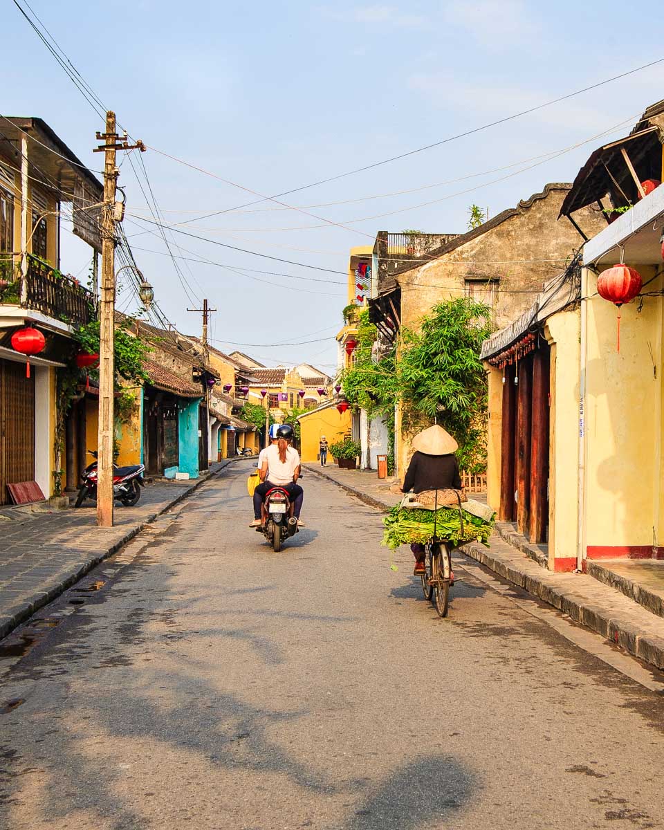 Hoi An Ancient Town locals ride bikes through street in Hoi An Vietnam