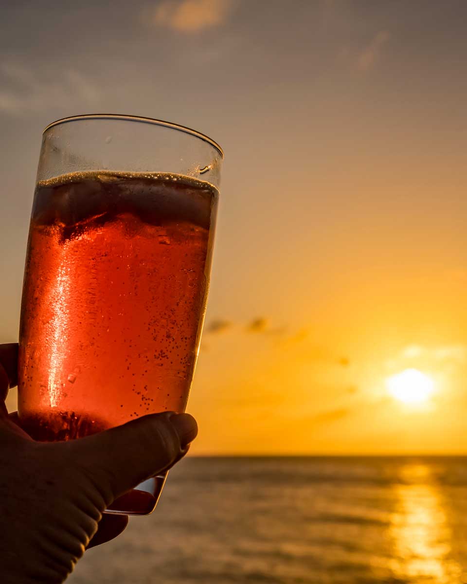 A-person-holds-a-cocktail-at-sunset-in-Bora Bora