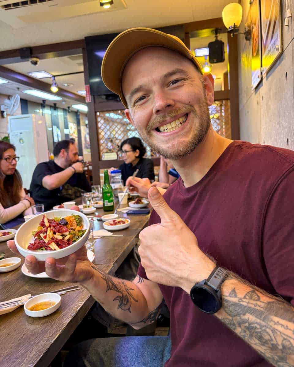 Evan eating a combination of raw beef tartare and fried rice on a food tour in Seoul South Korea