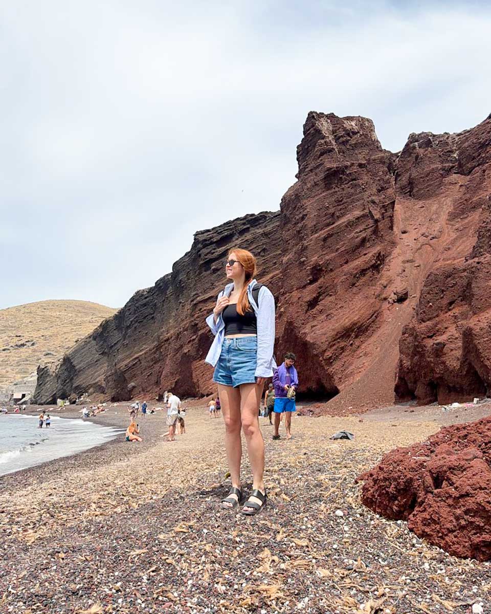Hannah standing on Red Beach with Santorini's red volcanic cliffs in the background