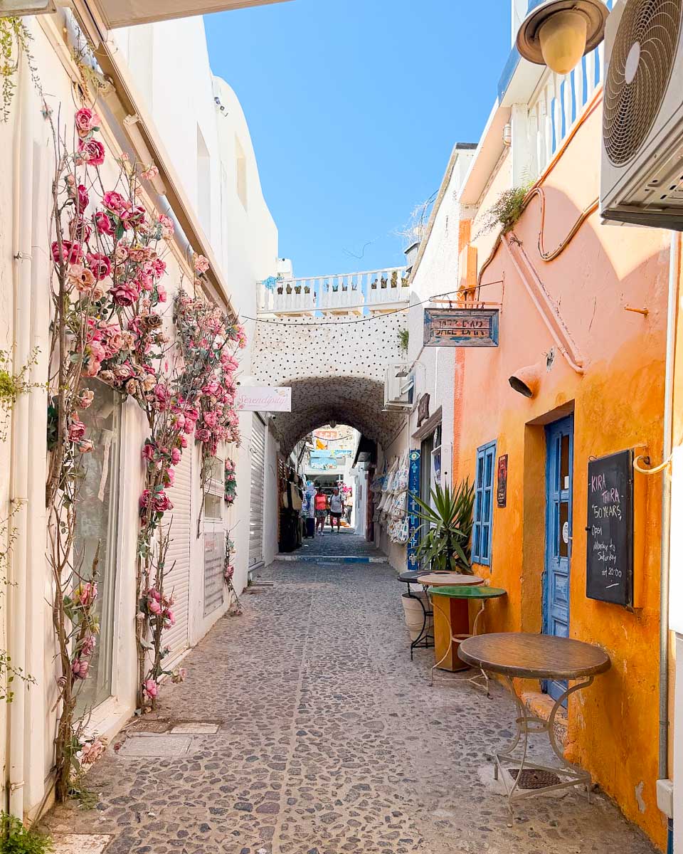 A beautiful street with flowers and stores in Fira, Santorini