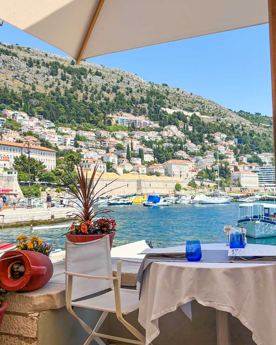 A table with a view over the Old Town Port at Gradska kavana Arsenal Restaurant in Dubrovnik