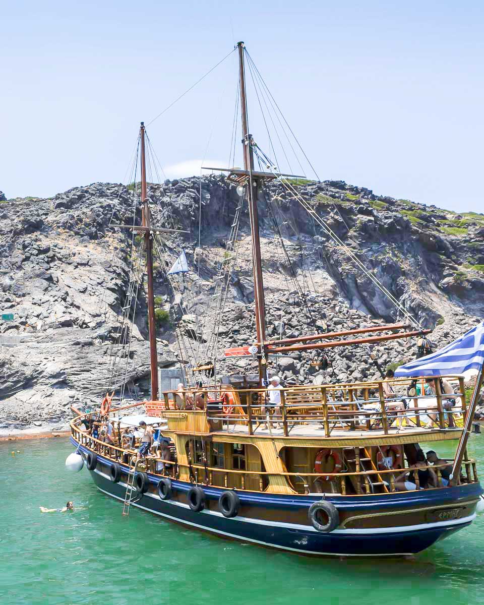 Traditional wooden sailboat anchored near Palea Kameni hot springs in Santorini