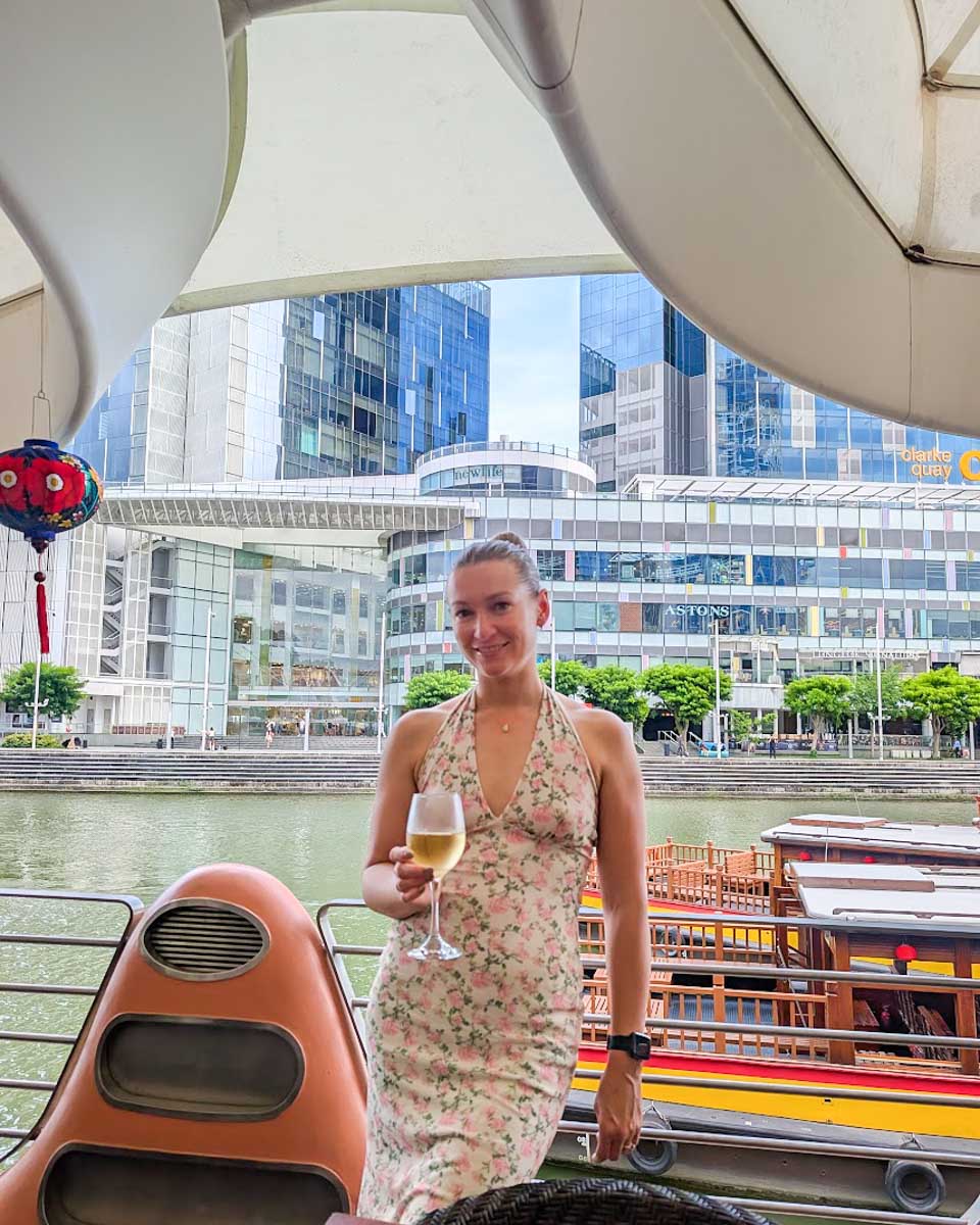 Bailey holding a glass of wine by the Singapore River