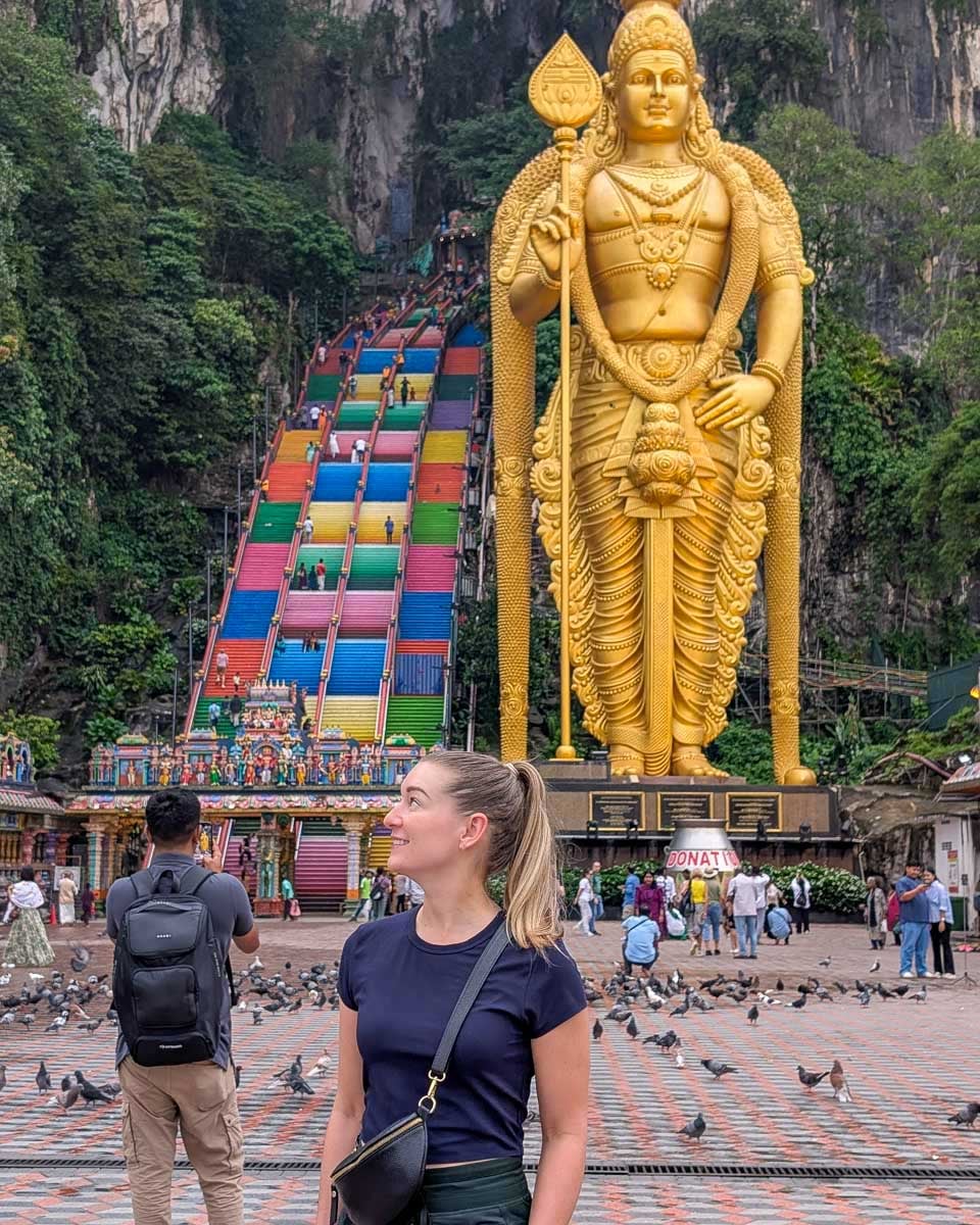 Bailey standing in front of the golden Lord Murugan statue at Batu Caves, Malaysia