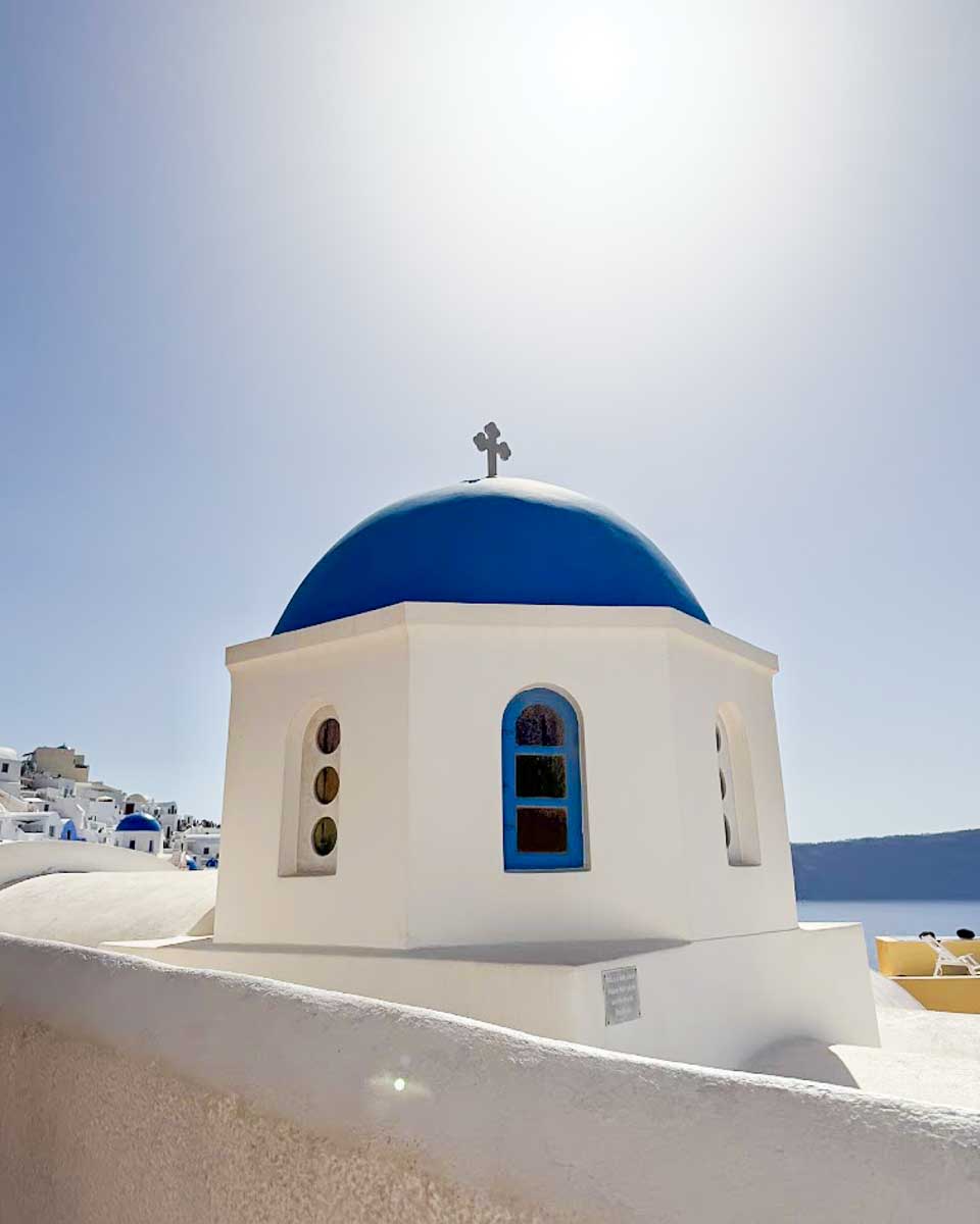 A blue-domed church beneath the bright sky in Oia, Santorini