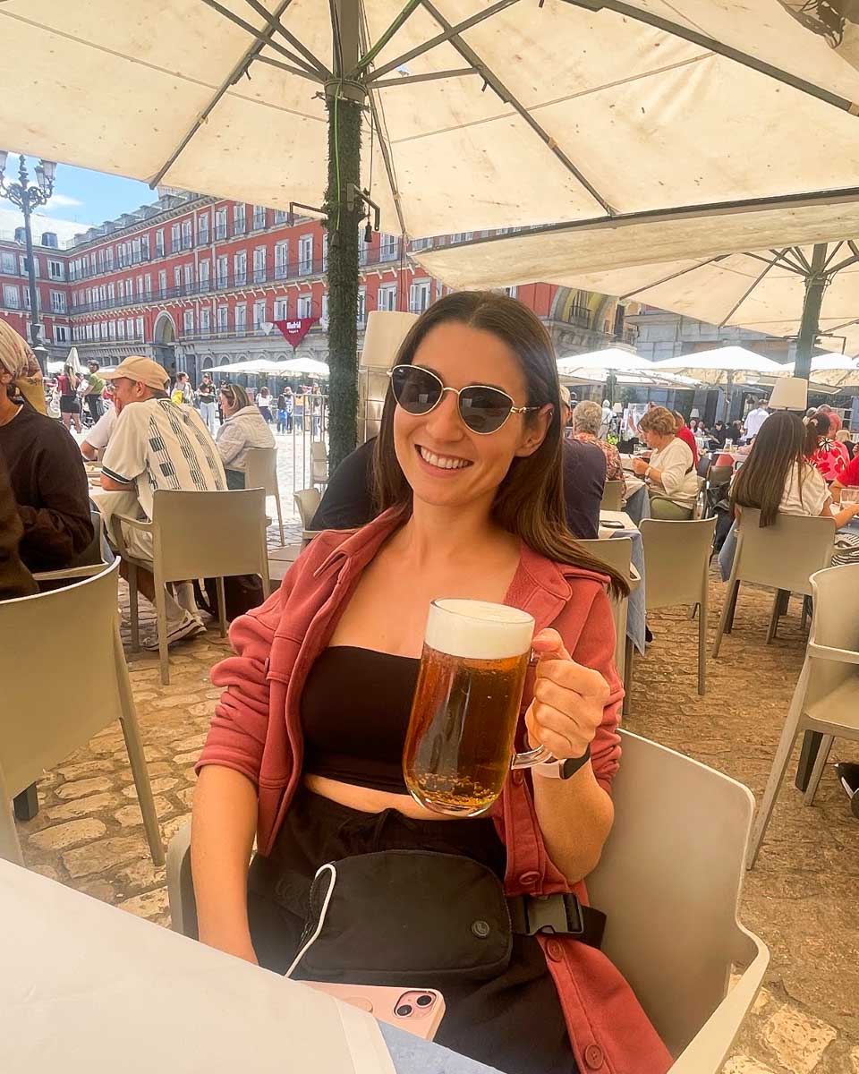 Brittni drinks a beer on a patio in Plaza Mayor Madrid