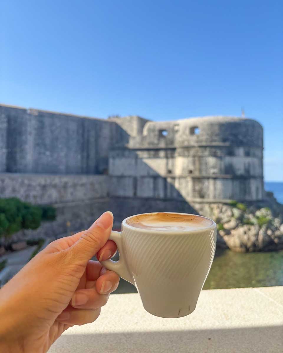 Brittni hold up her cappuccino at Dubravka 1836 Restaurant in Dubrovnik