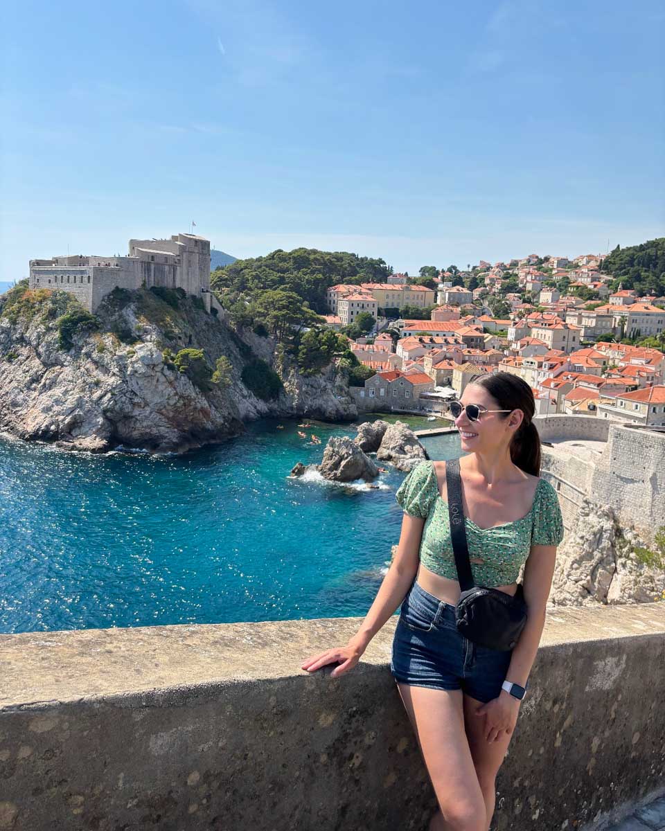 Brittni poses while walking the city walls in Dubrovnik with Fort Lovrjenac in the background
