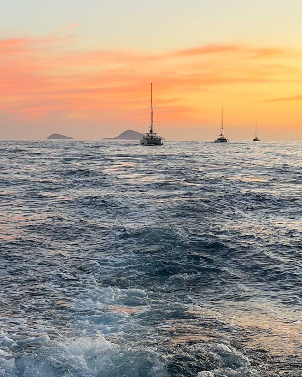 Catamaran sailing across the Aegean Sea during sunset in Santorini