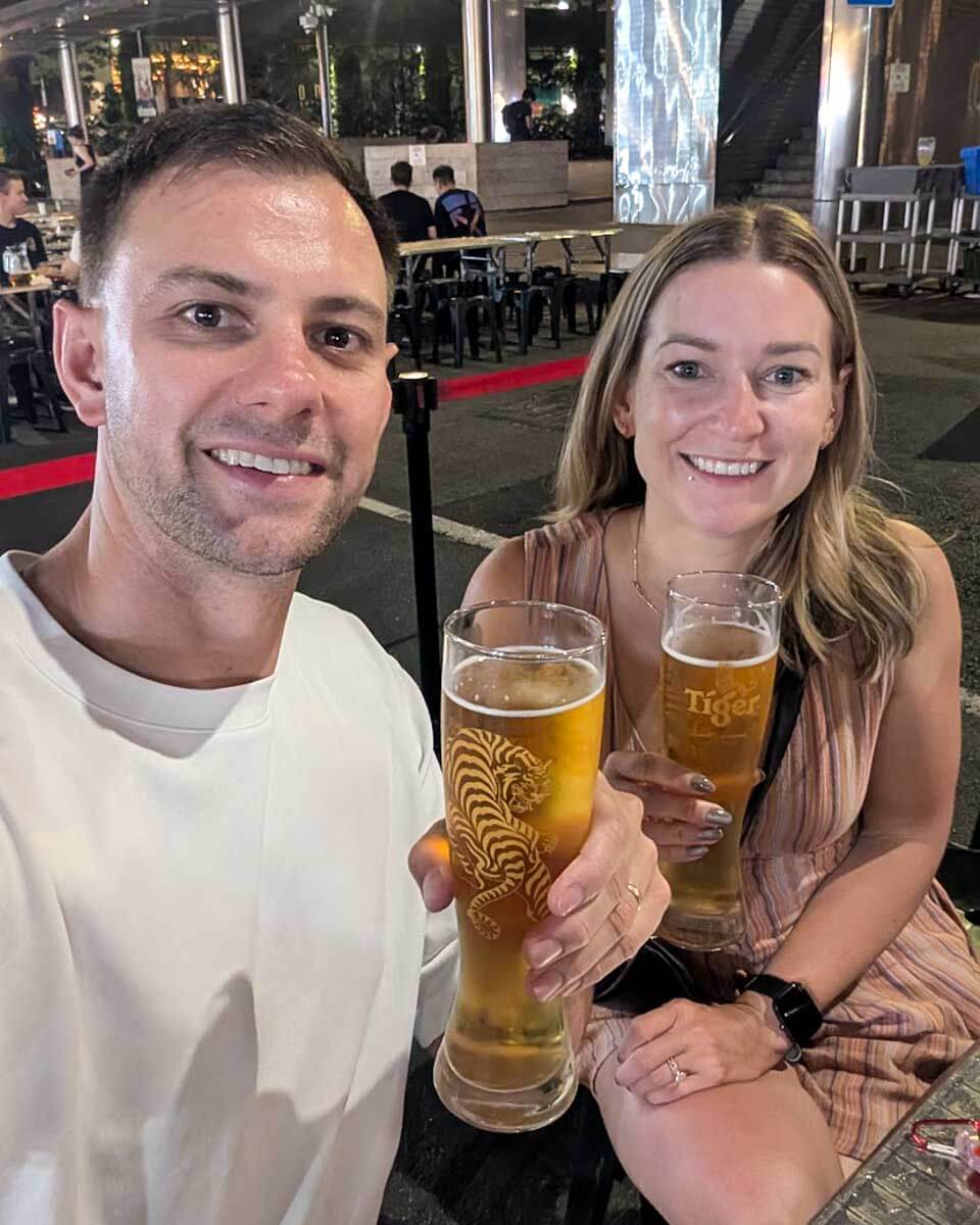 Daniel and Bailey holding glasses of beer at a restaurant in Singapore