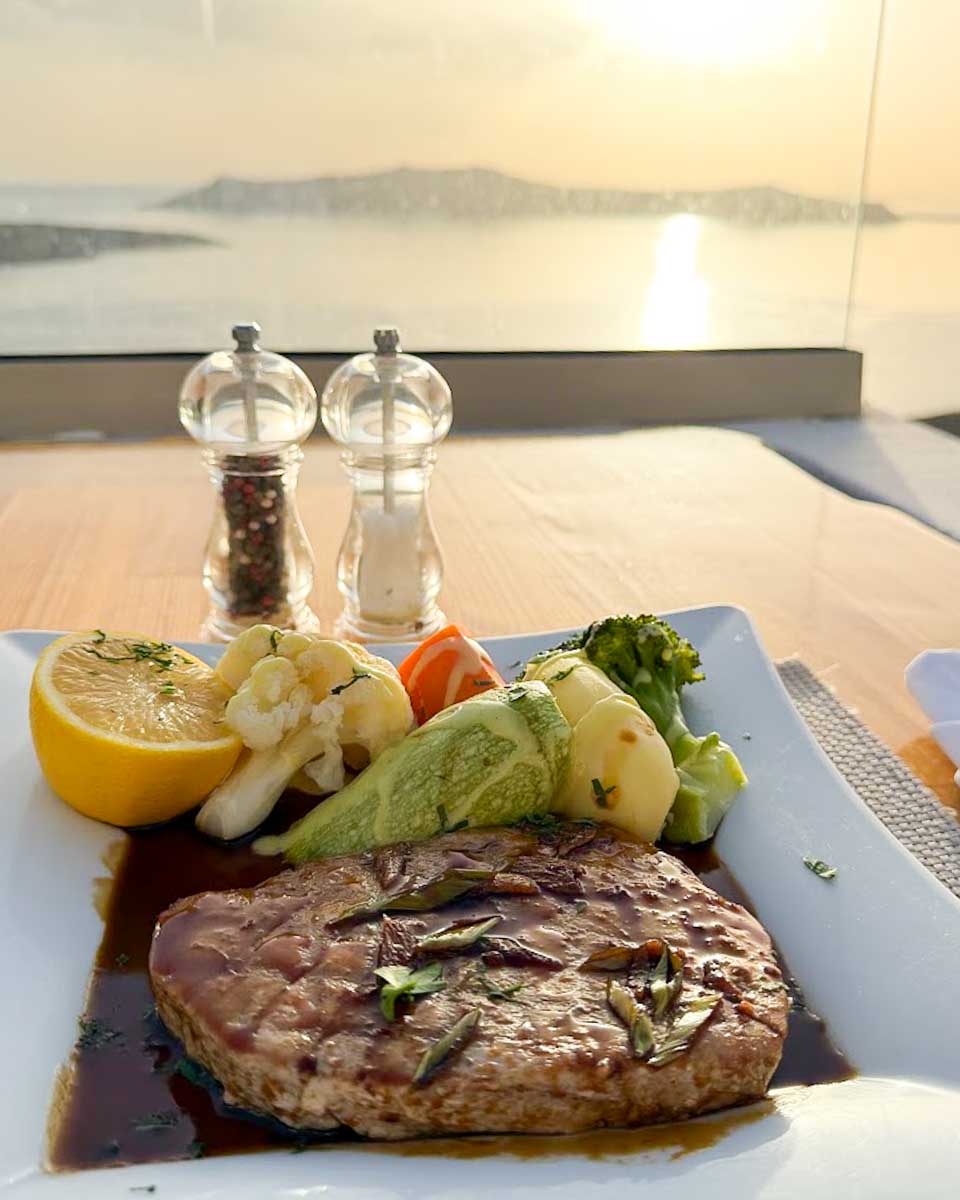 Grilled steak served with vegetables at Aris Restaurant overlooking the Santorini sunset
