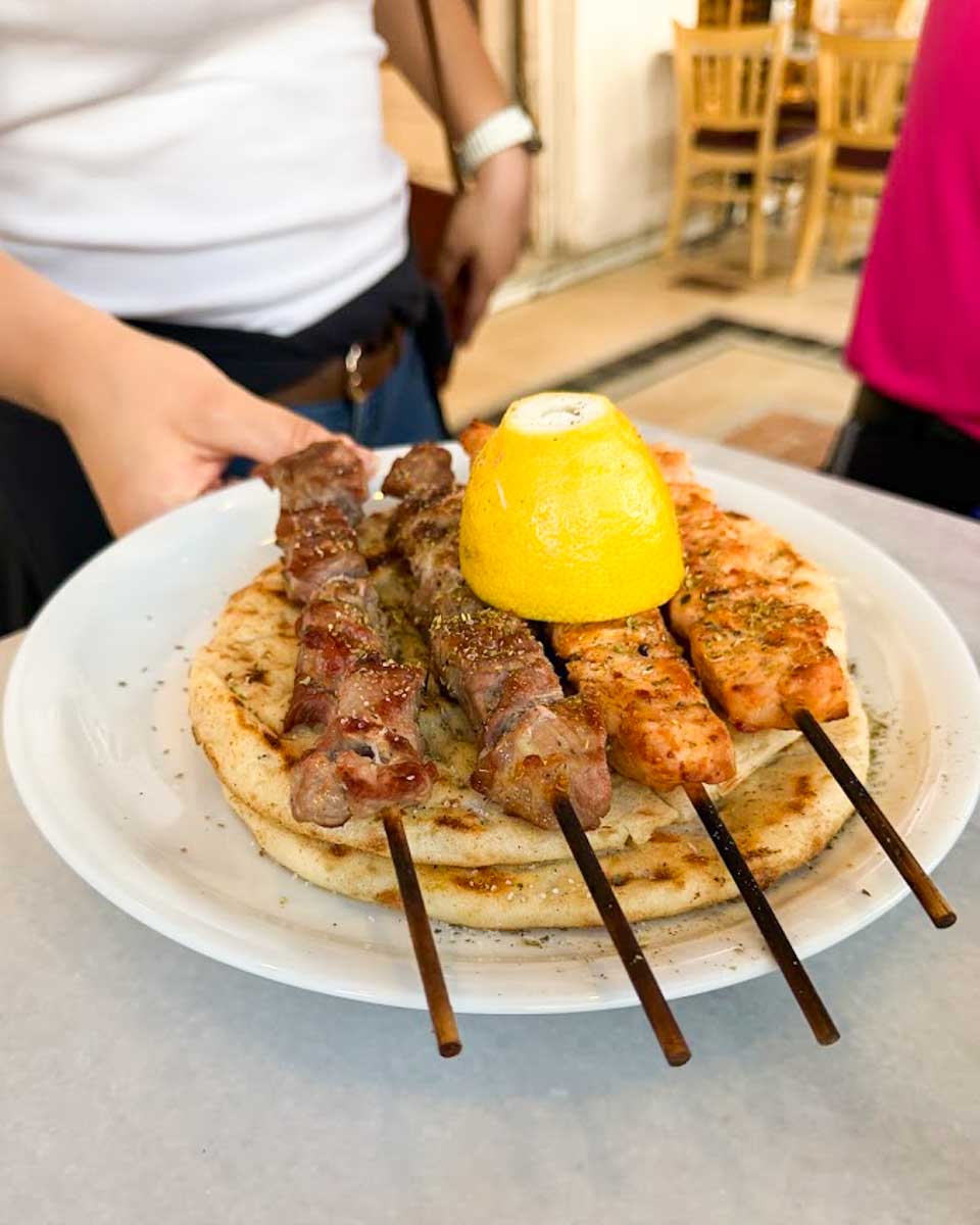 Hannah enjoying souvlaki skewers during a food tour in Athens