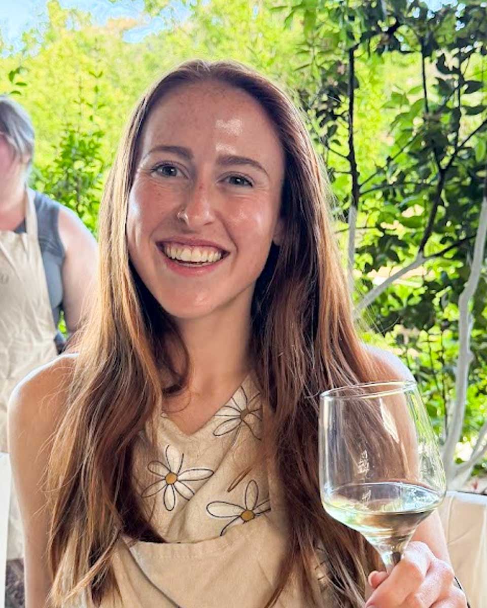 Hannah holding a glass of white wine during a wine tasting at a historic vineyard in Naxos