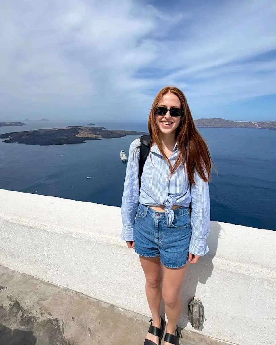 Hannah standing at a viewpoint overlooking the Santorini caldera in Firostefani