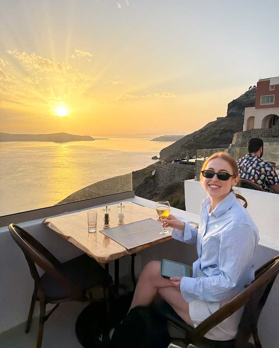 Hannah enjoying dinner with caldera views at sunset in Fira, Santorini