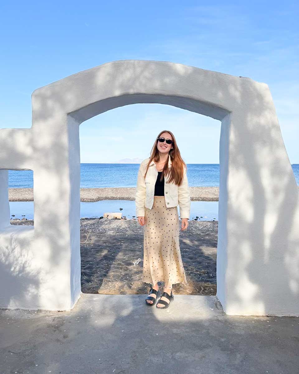 Hannah standing beneath a white arch during a wine tour in Santorini