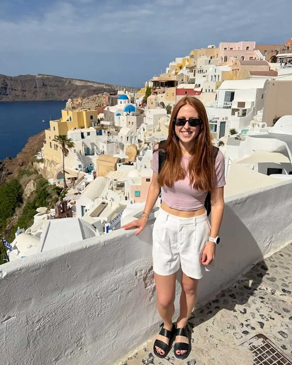 Hannah posing at a viewpoint overlooking Oia and Santorini's caldera