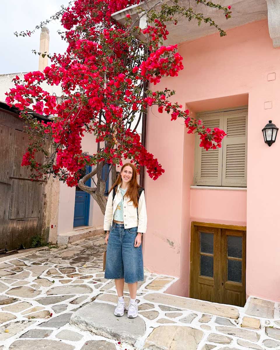 Hannah standing outside a pink colored house in Naxos, Greece