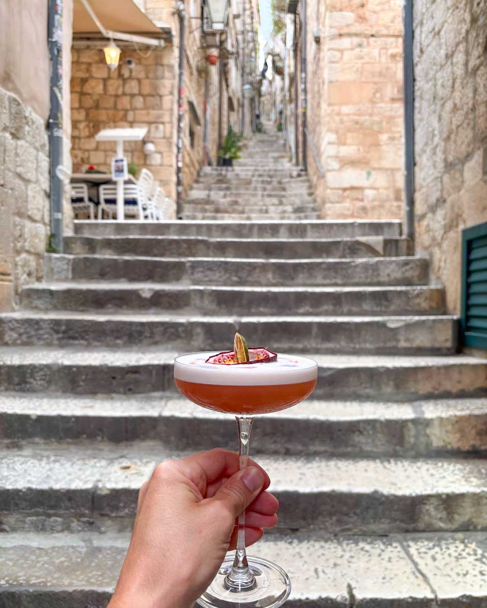 Jesse holds up a cocktail from the Bar in Dubrovnik