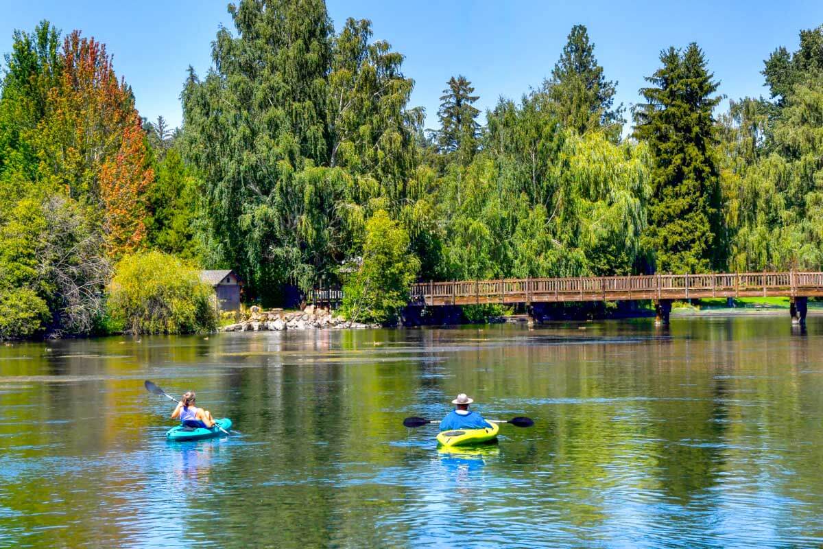 People kayak down the Deschutes River from Drake Park in Bend Oregon