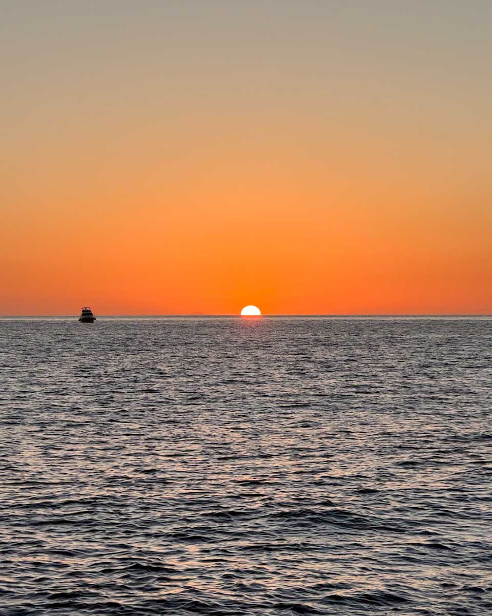 Sunset over the Aegean Sea viewed from a catamaran in Santorini