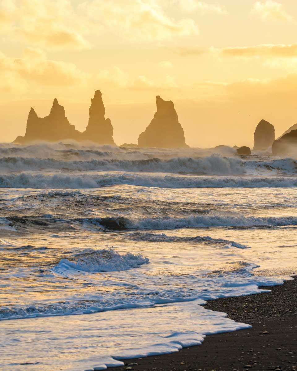 Sunset with golden sky behind the Reynisdrangar rocks in Vik, Iceland