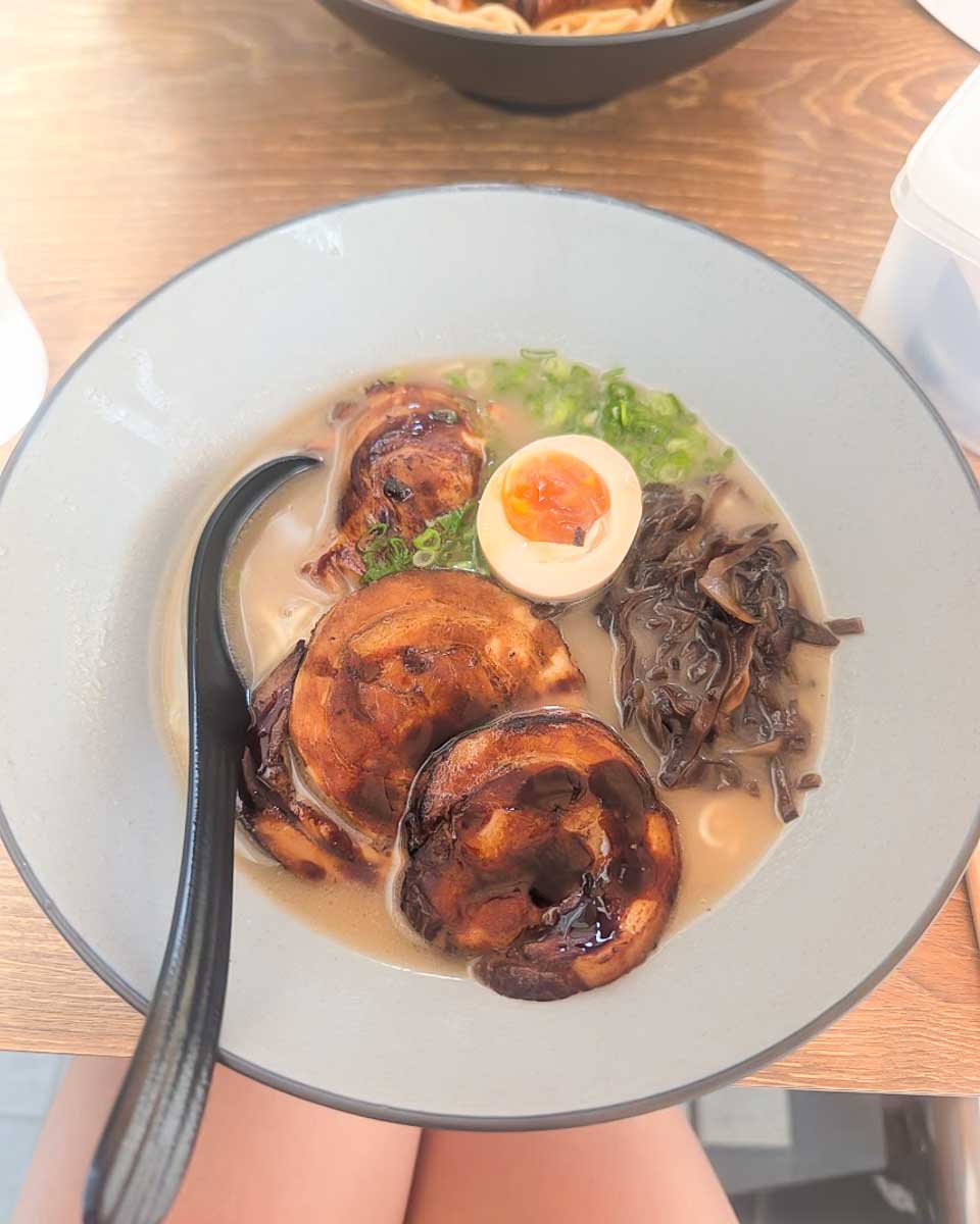 A bowl of ramen topped with egg and meat in Singapore