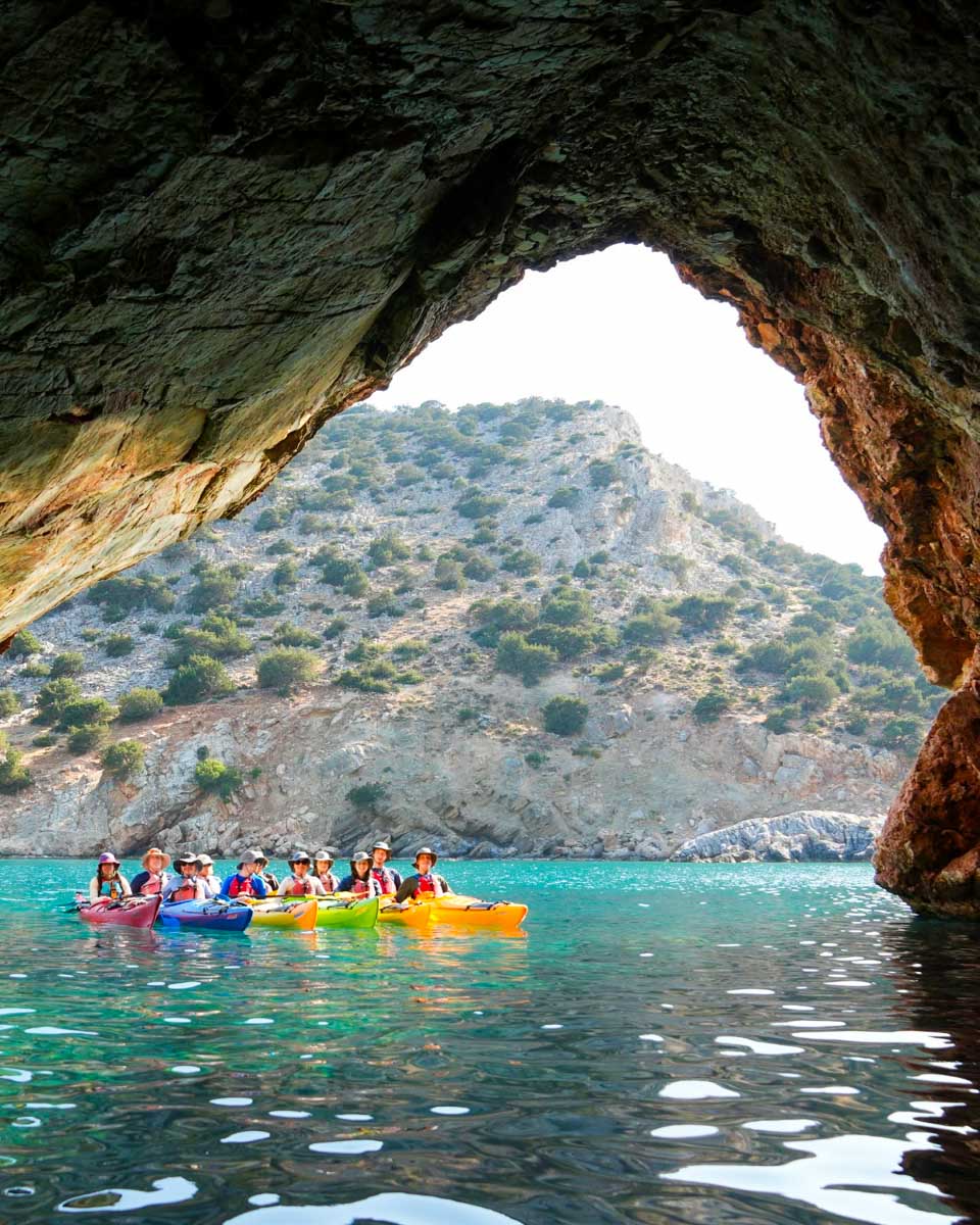 People kayaking into Rina Cave during a sea kayaking tour in Naxos